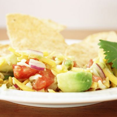 This super fresh tex-mex dip is unlike anything else I've ever had. Fresh avocado, red onion, and tomatoes combine with shredded cheese and a hint of green taco sauce to make a delicious dip.