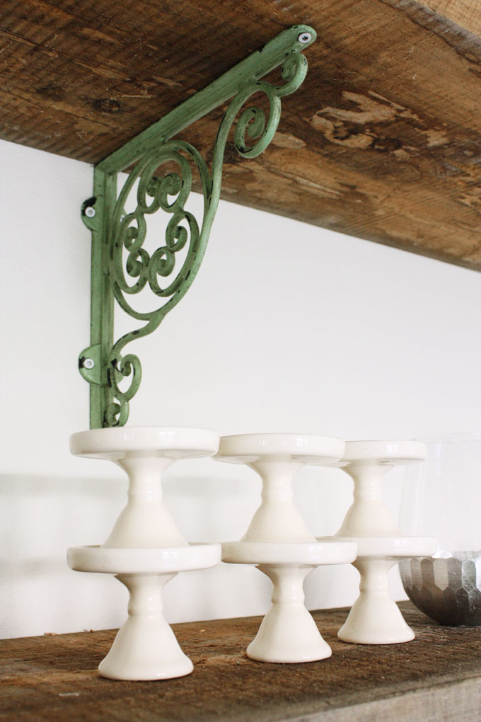 A finished basement studio with open shelves made of reclaimed barnwood and decorative green brackets from Anthropologie | modern farmhouse inspiration