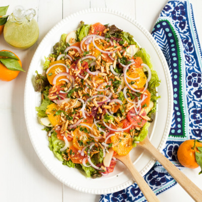 This salad is a family favorite! Tender red leaf lettuce salad is topped with thinly sliced apples, fresh oranges, red onions, and homemade sugared almonds, with an herby, from-scratch vinaigrette to top it all off.