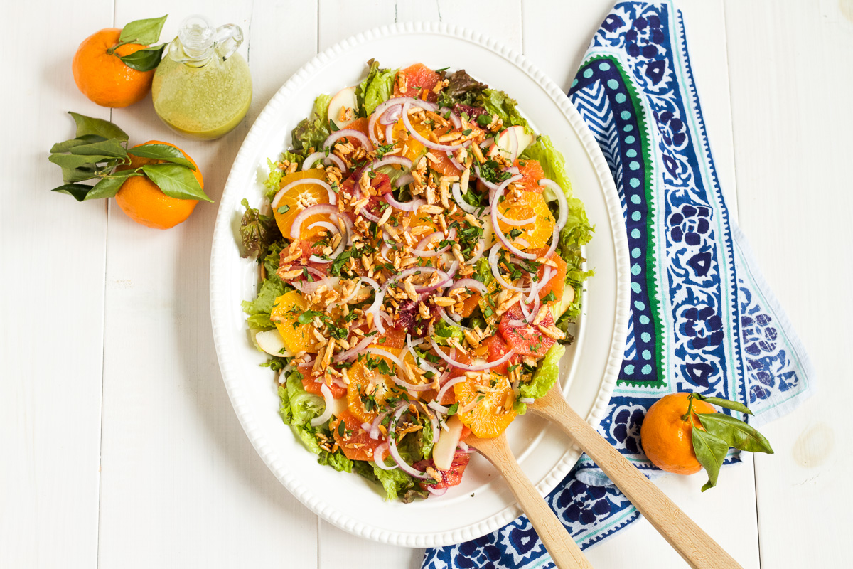 This salad is a family favorite! Tender red leaf lettuce salad is topped with thinly sliced apples, fresh oranges, red onions, and homemade sugared almonds, with an herby, from-scratch vinaigrette to top it all off.