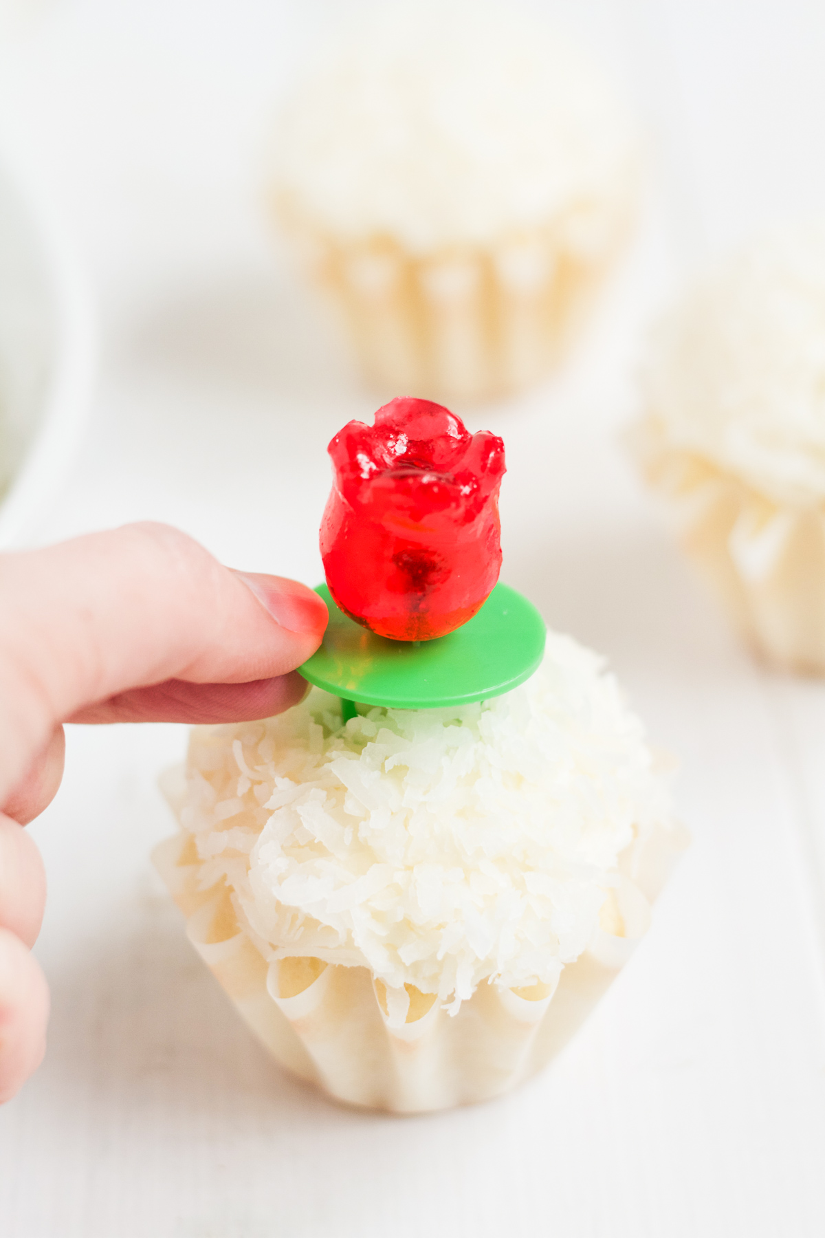 Coconut cupcakes with coconut buttercream and coconut topping, with tulip-shaped ring pops for decoration.