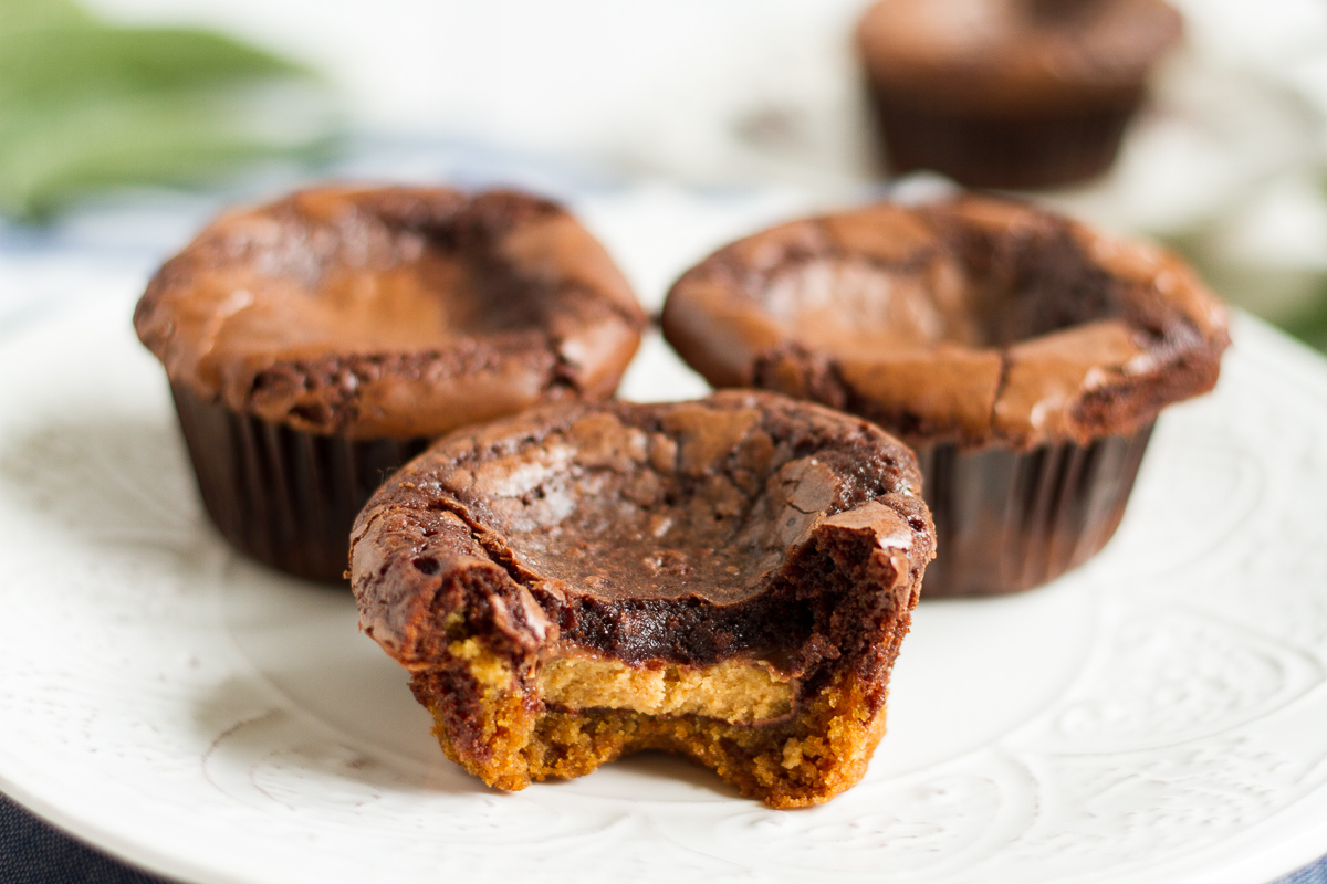 These may look like unassuming brownies baked in cupcake tins, but once you unwrap them, you'll see they have a peanut butter cookie base! And even better, there's a peanut butter cup hidden in the middle!