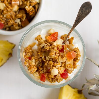 Crunchy homemade granola with oats, sunflower seeds, macadamia nuts, coconut chips, dried tropical fruits likes pineapple, mango, and papaya, lightly sweetened with honey and brown sugar.