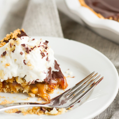 An over-the-top pie featuring a homemade graham cracker crust, a layer of macadamia nut-filled caramel, and a topping of rich chocolate ganache.